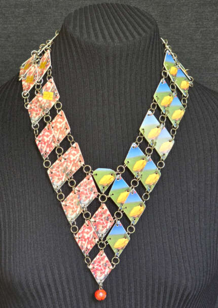 Colar criado em cartão telefônico com corte triangular, com metade das cores do Brasil e outras cores da Suíca.